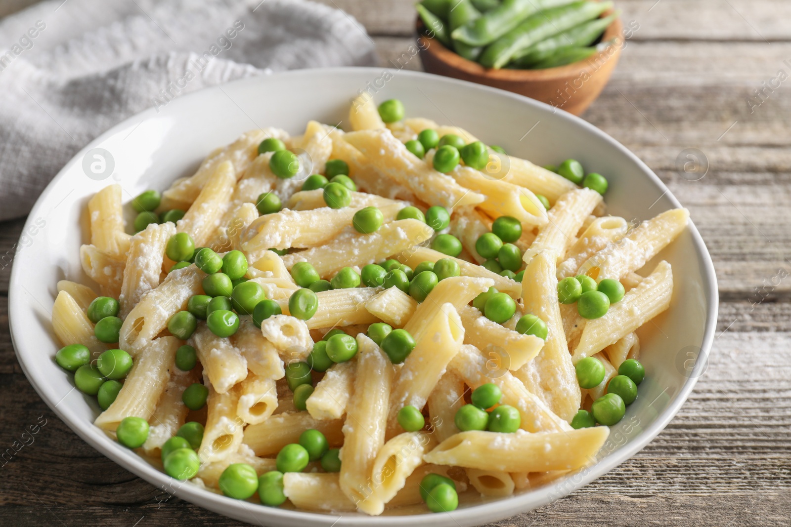 Photo of Delicious pasta with green peas and cheese on wooden table, closeup