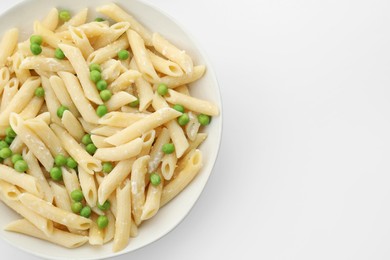 Delicious pasta with green peas and cheese in bowl on white background, top view. Space for text