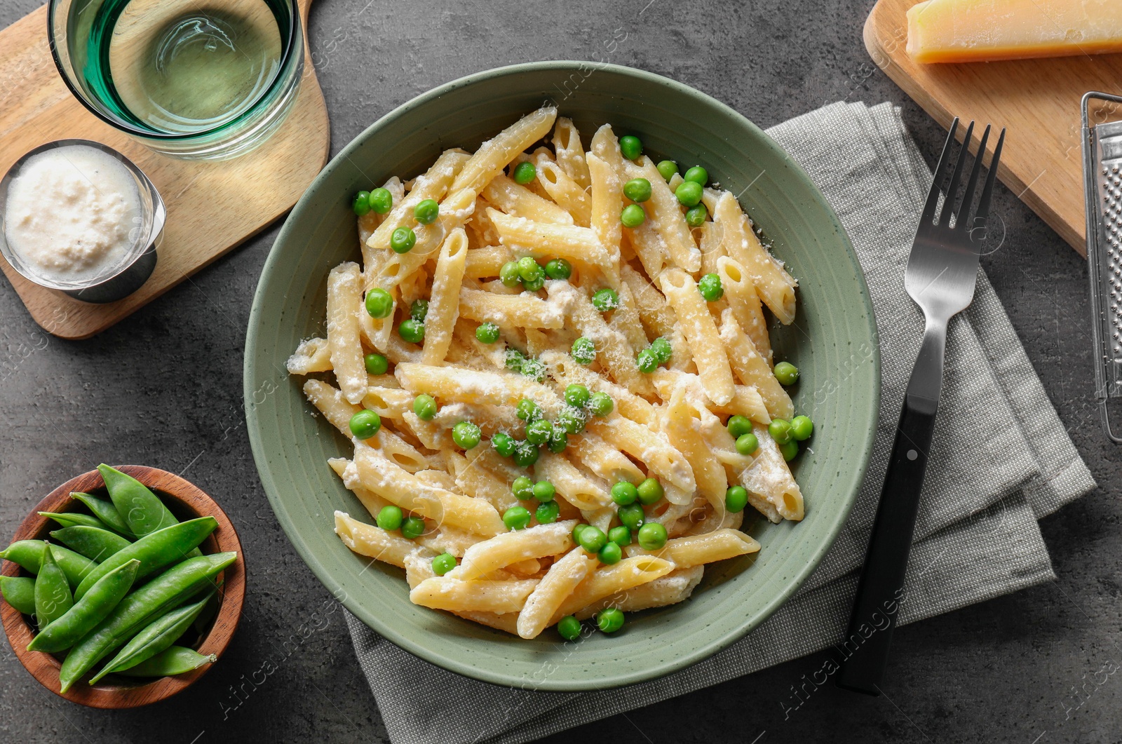 Photo of Delicious pasta with green peas served on grey table, top view