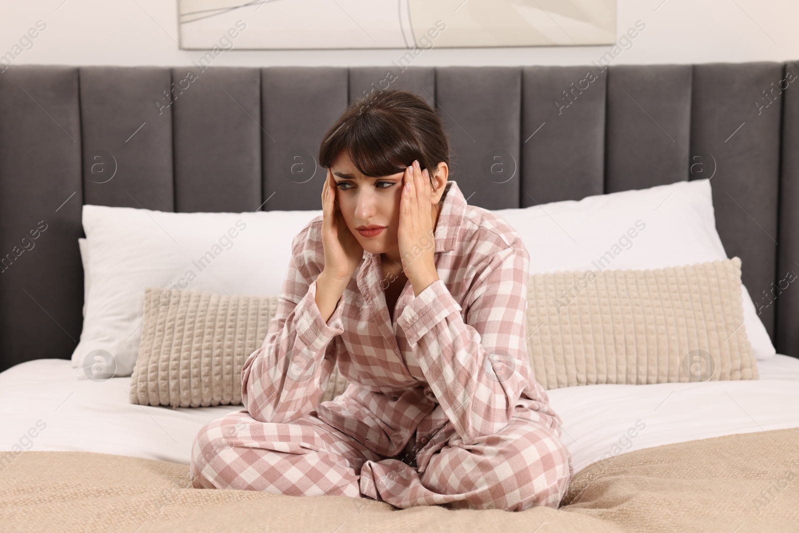 Photo of Upset woman suffering from headache on bed at home