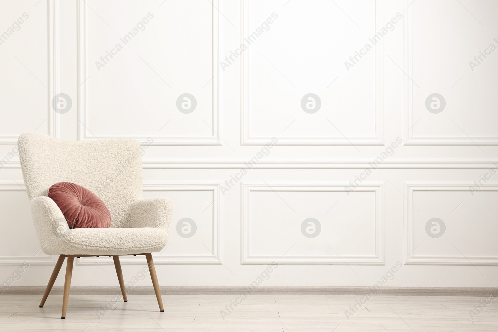 Photo of Soft armchair with pillow in light room. Space for text