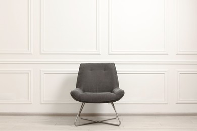 Photo of One soft armchair near white wall indoors