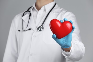 Photo of Doctor with red heart on grey background, selective focus