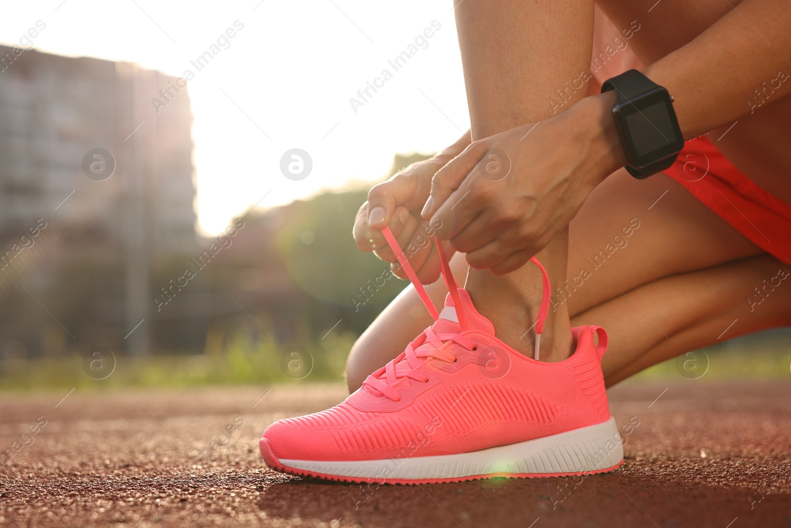 Photo of Woman tying shoelace of pink sneaker at stadium, closeup. Space for text