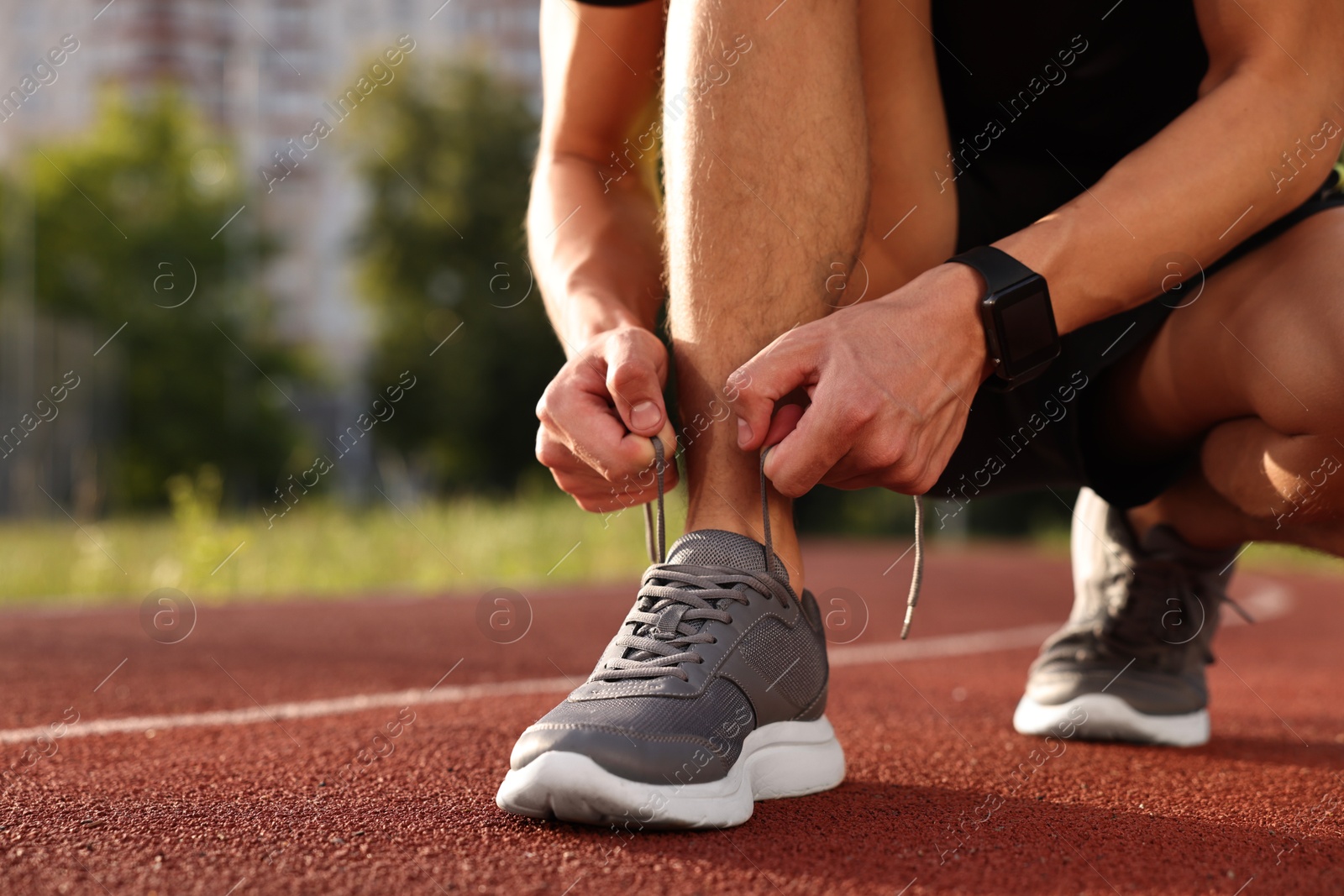 Photo of Man tying shoelace of grey sneaker at stadium, closeup. Space for text