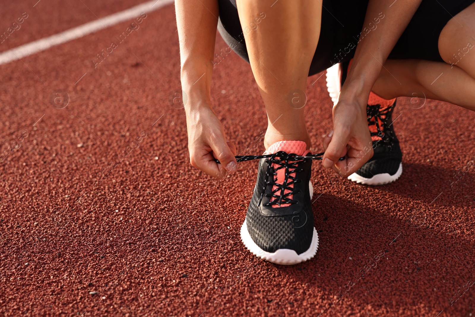 Photo of Woman tying shoelace of sneaker at stadium, closeup. Space for text