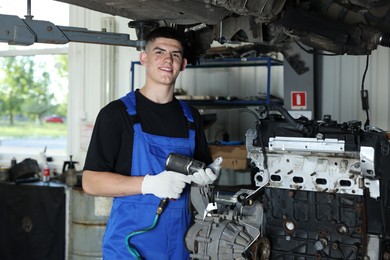 Photo of Young auto mechanic fixing motor at automobile repair shop. Car diagnostic