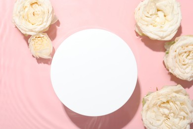 Photo of Beautiful rose flowers and round shaped podium in water on pink background, flat lay