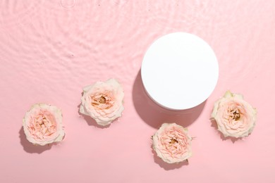 Photo of Beautiful rose flowers and round shaped podium in water on pink background, flat lay. Space for text