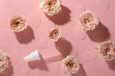 Photo of Beautiful rose flowers, pipette and drops of cosmetic serum on pink background, flat lay