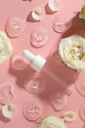 Photo of Beautiful rose flowers, pipette and drops of cosmetic serum on pink background, flat lay