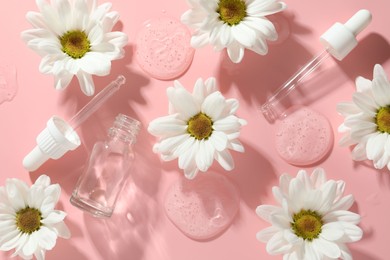 Photo of Beautiful daisy flowers, cosmetic bottle, pipettes and drops of serum on pink background, flat lay