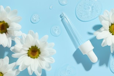 Photo of Beautiful daisy flowers, pipette and drops of cosmetic serum on light blue background, flat lay