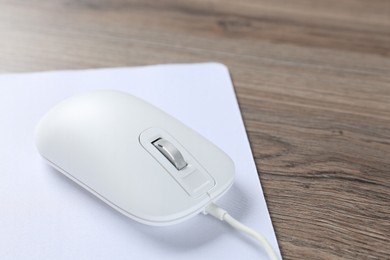 Photo of Computer mouse with mousepad on wooden desk, closeup