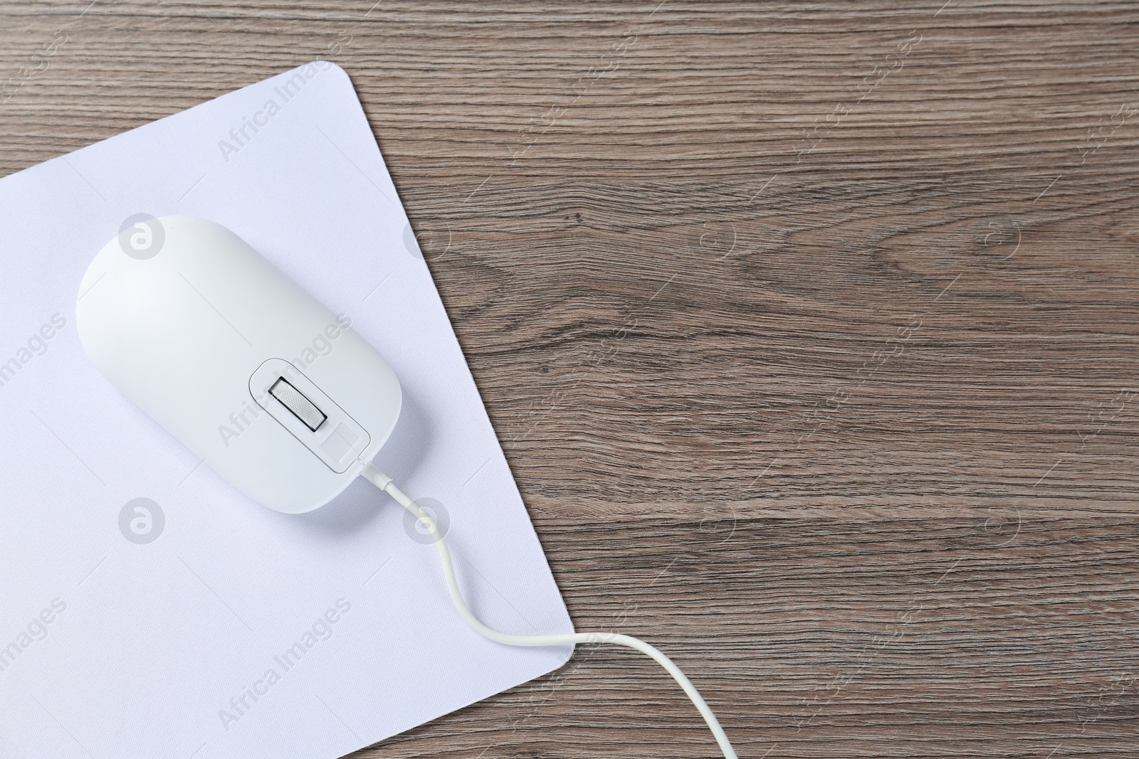 Photo of Computer mouse with mousepad on wooden desk, top view. Space for text