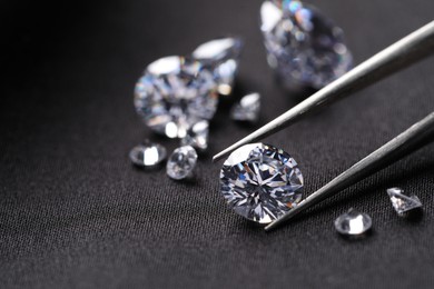 Tweezers with beautiful shiny diamonds on black fabric, closeup