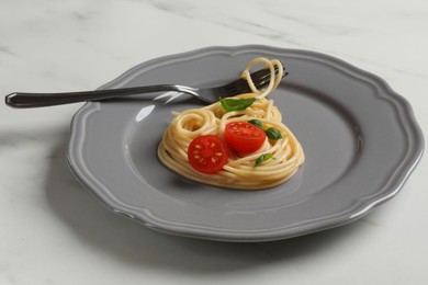 Photo of Heart made of tasty spaghetti, fork, tomato and basil on white marble table