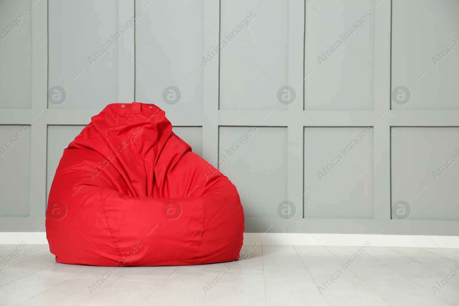 Photo of Red bean bag chair near grey wall indoors. Space for text