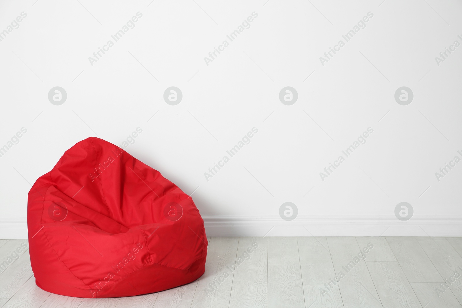 Photo of Red bean bag chair near white wall in room