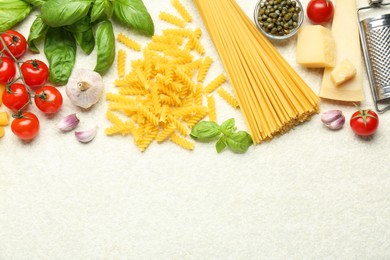 Photo of Different types of pasta, grater, spices and products on light table, flat lay. Space for text