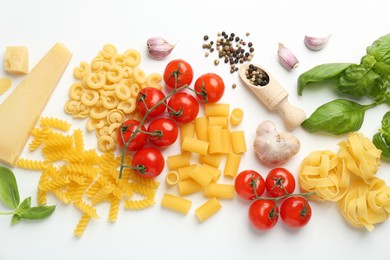 Different types of pasta, spices and products on white background, top view