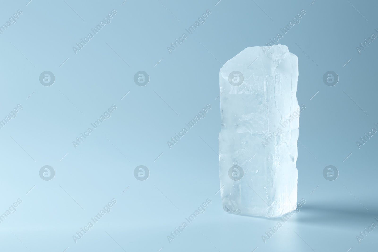 Photo of Blocks of clear ice on light blue background, space for text