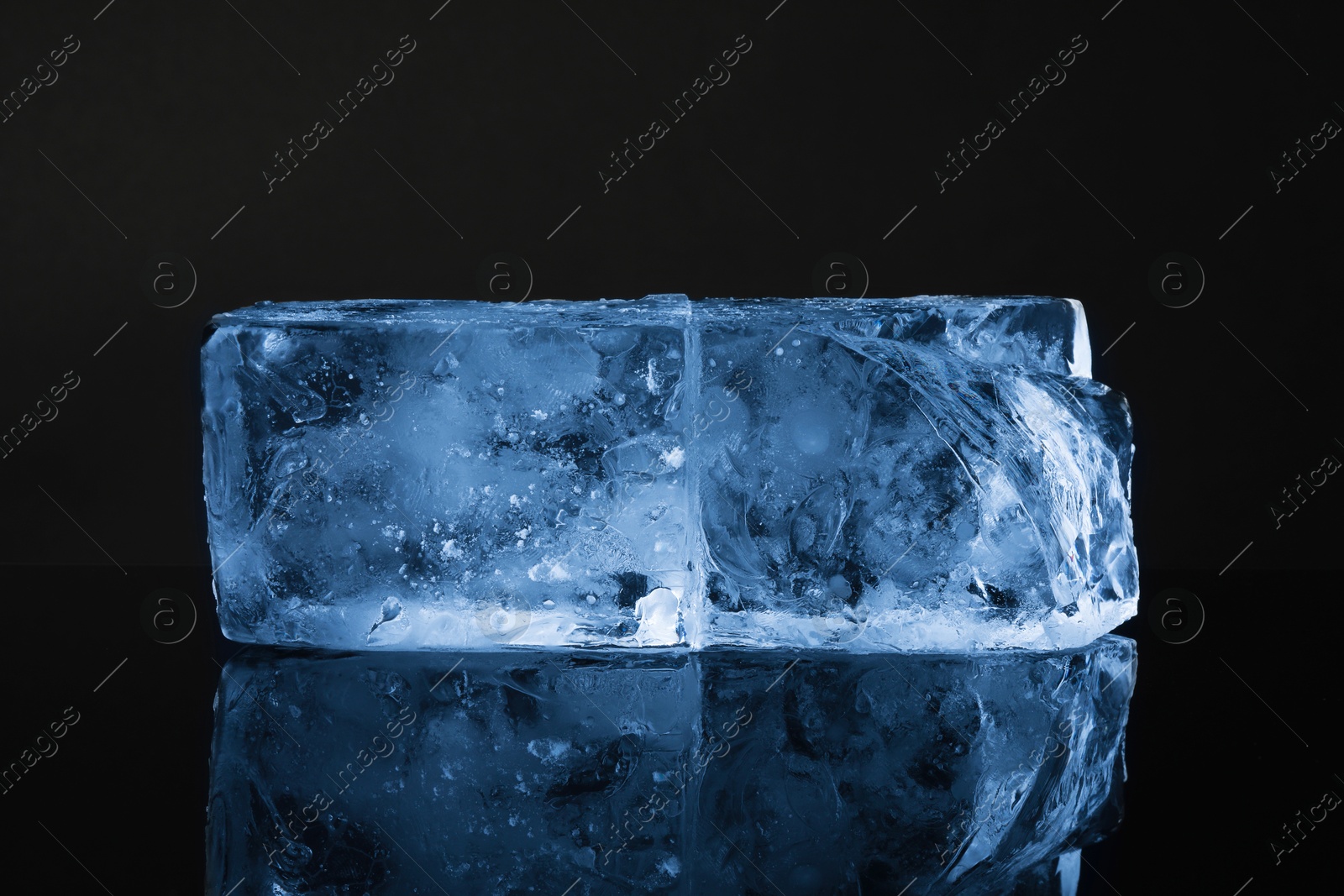 Photo of Blocks of clear ice on black mirror surface