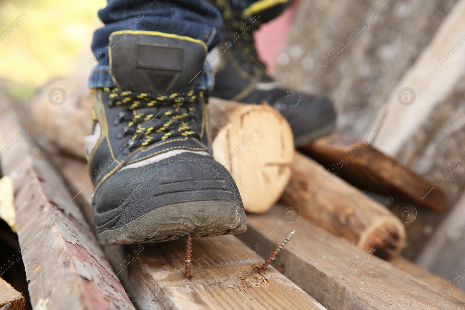 Photo of Careless worker stepping on nail in wooden plank outdoors, closeup