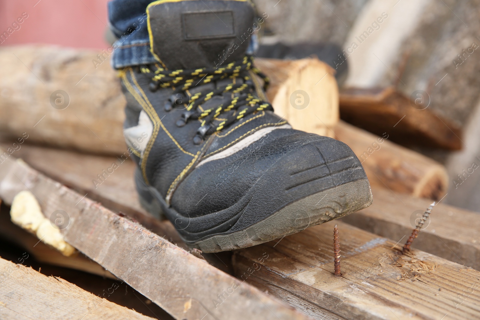 Photo of Careless worker stepping on nail in wooden plank outdoors, closeup