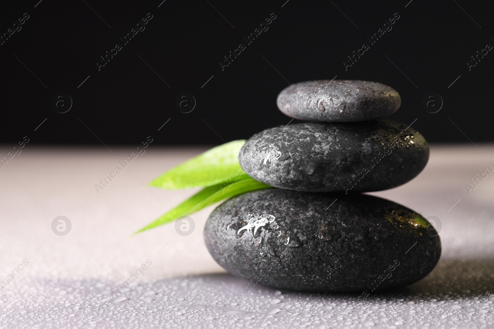 Photo of Wet spa stones and green leaves on grey background