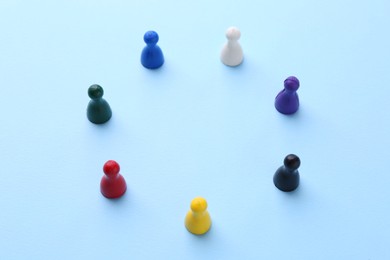 Photo of Equality concept. Different game pieces on light blue background, above view