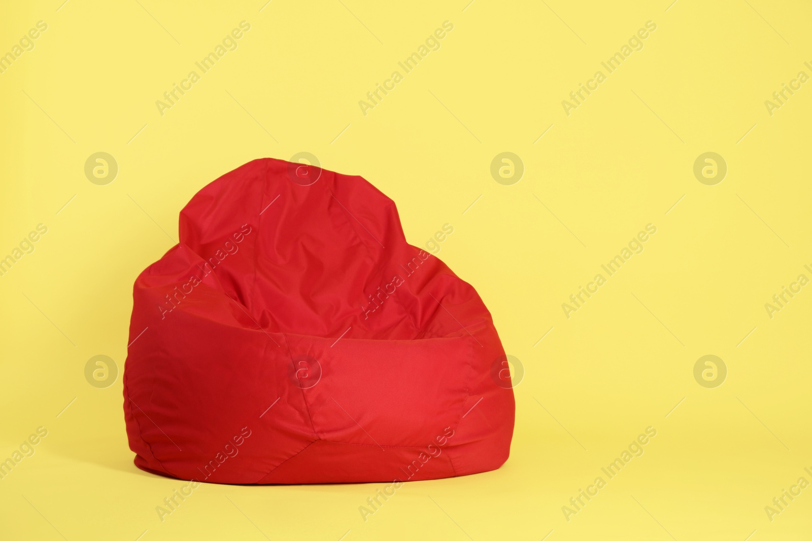 Photo of Red bean bag chair on yellow background, space for text