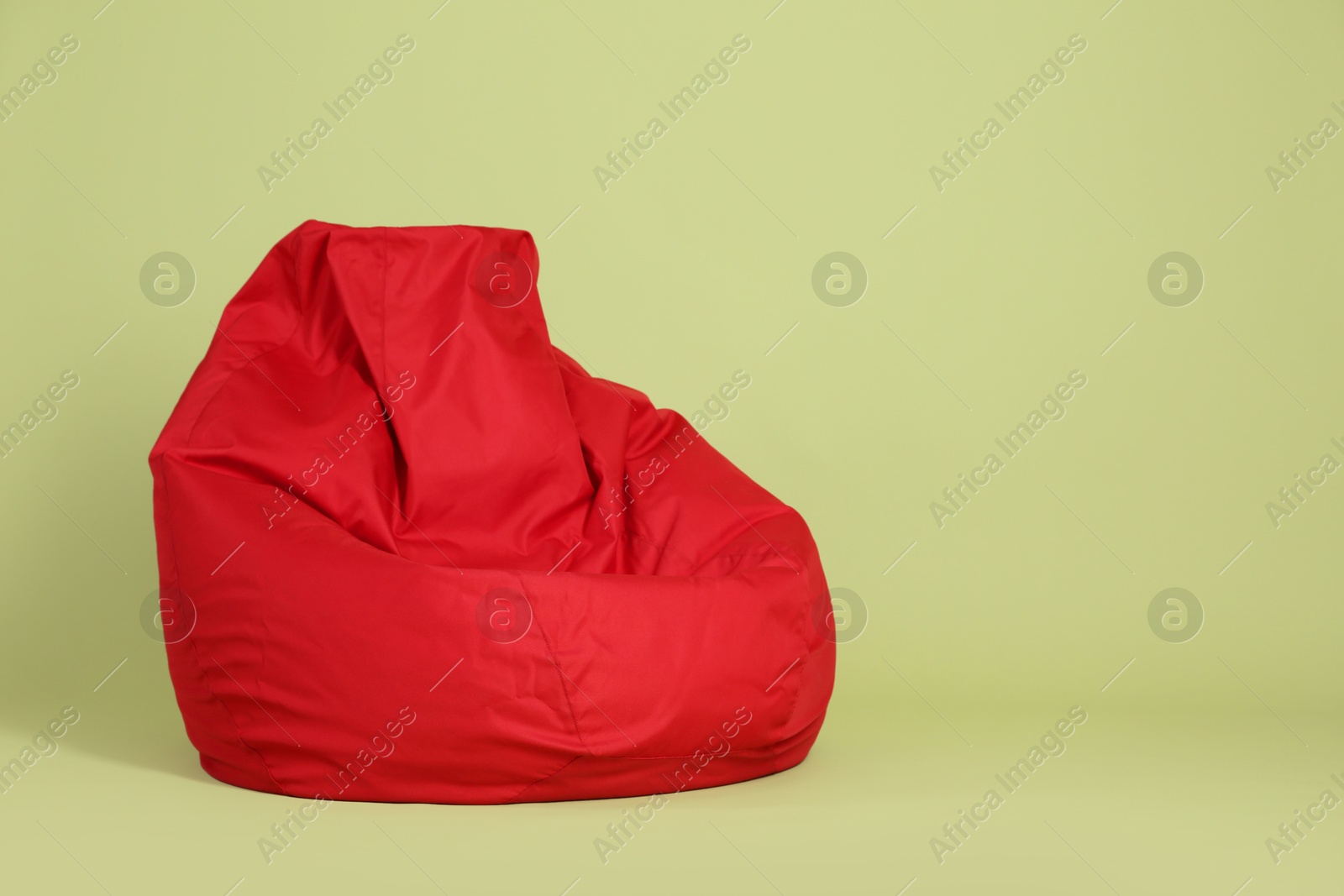 Photo of Red bean bag chair on olive background, space for text