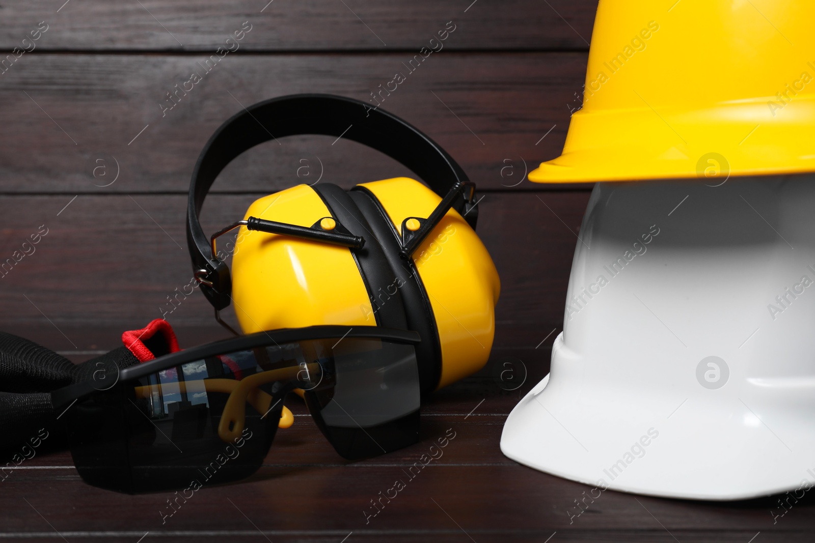 Photo of Hard hats, earmuffs, gloves and protective goggles on wooden surface