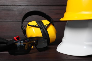 Photo of Hard hats, earmuffs, gloves and protective goggles on wooden surface