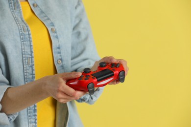 Photo of Woman playing video games with controller on yellow background, closeup. Space for text
