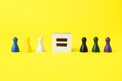 Photo of Game pieces of different colors and equal sign on yellow background