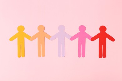 Photo of Equality concept. Paper human figures of different colors on pink background, top view
