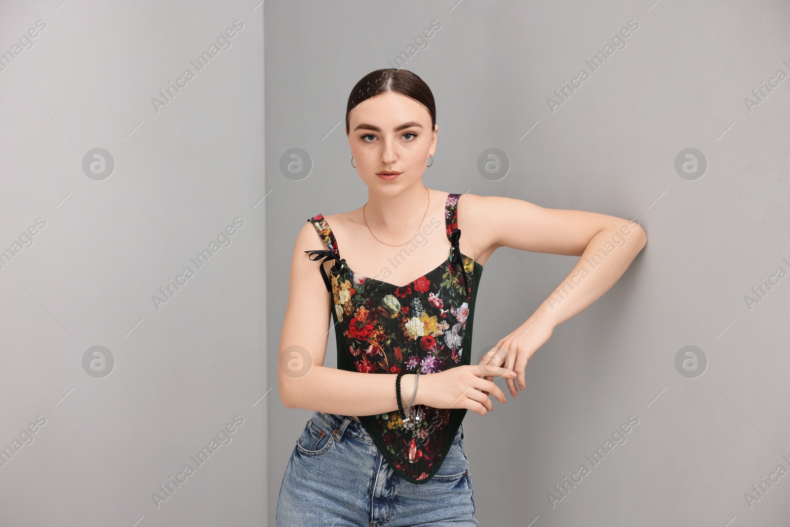 Photo of Beautiful young woman in stylish corset near grey wall