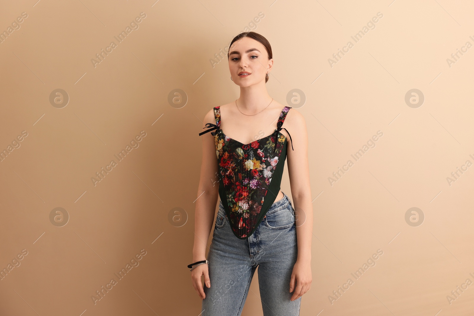 Photo of Beautiful young woman in stylish corset on beige background