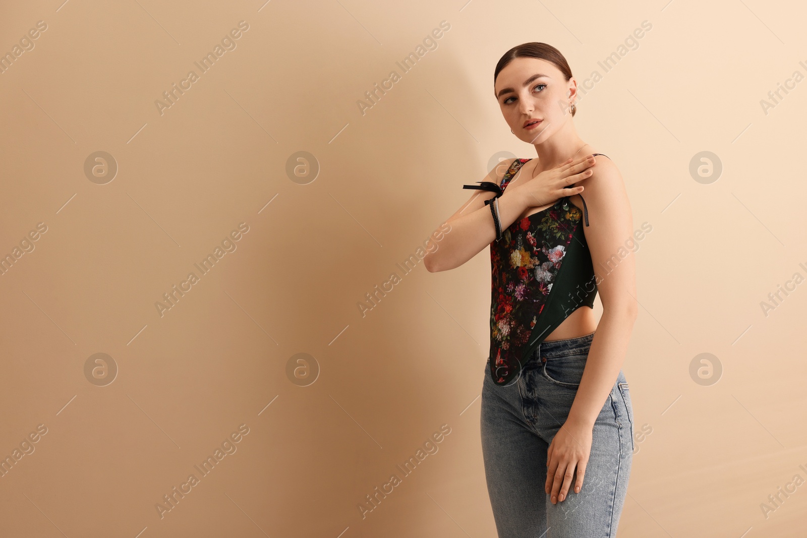 Photo of Beautiful young woman in stylish corset on beige background. Space for text