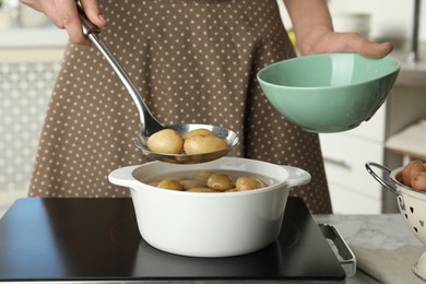 Woman taking potatoes from pot on stove, closeup