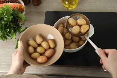 Photo of Woman taking potatoes from pot on stove, closeup