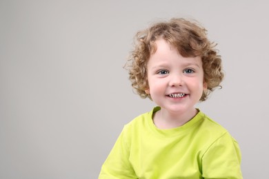 Photo of Portrait of cute little boy on grey background, space for text