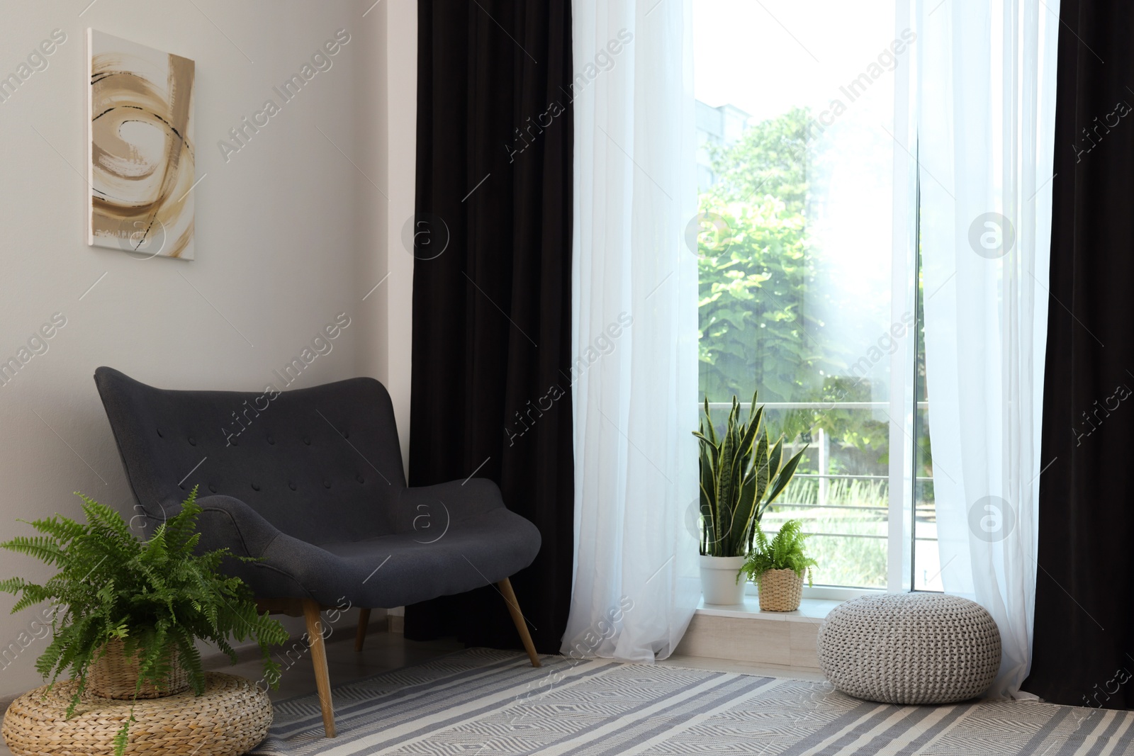 Photo of Sofa, green houseplants, pouffe and elegant curtains in room. Interior design