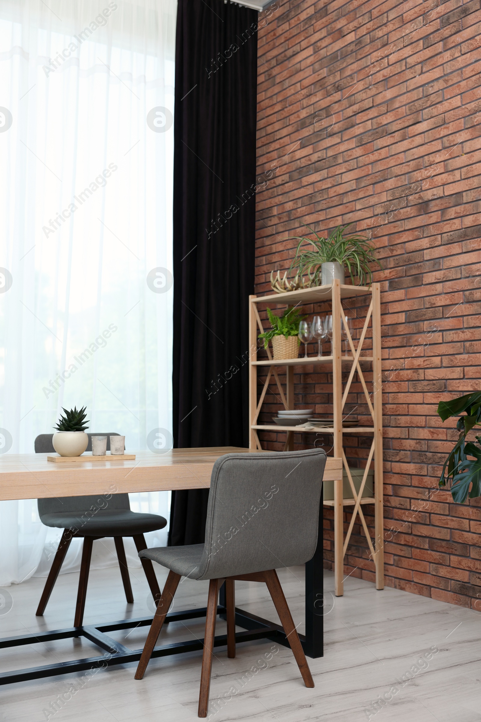 Photo of Shelving unit, table, chairs, green houseplants and elegant curtain in room. Interior design