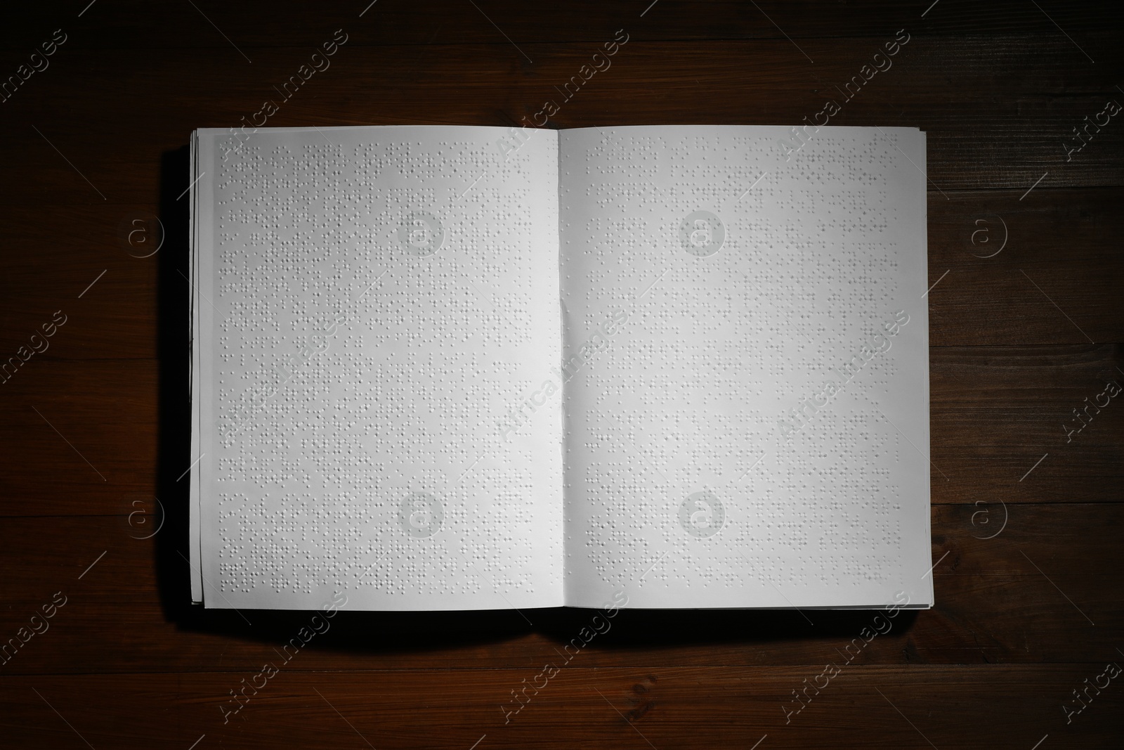 Photo of Book with Braille text on wooden table, top view. Education and leisure for blind people