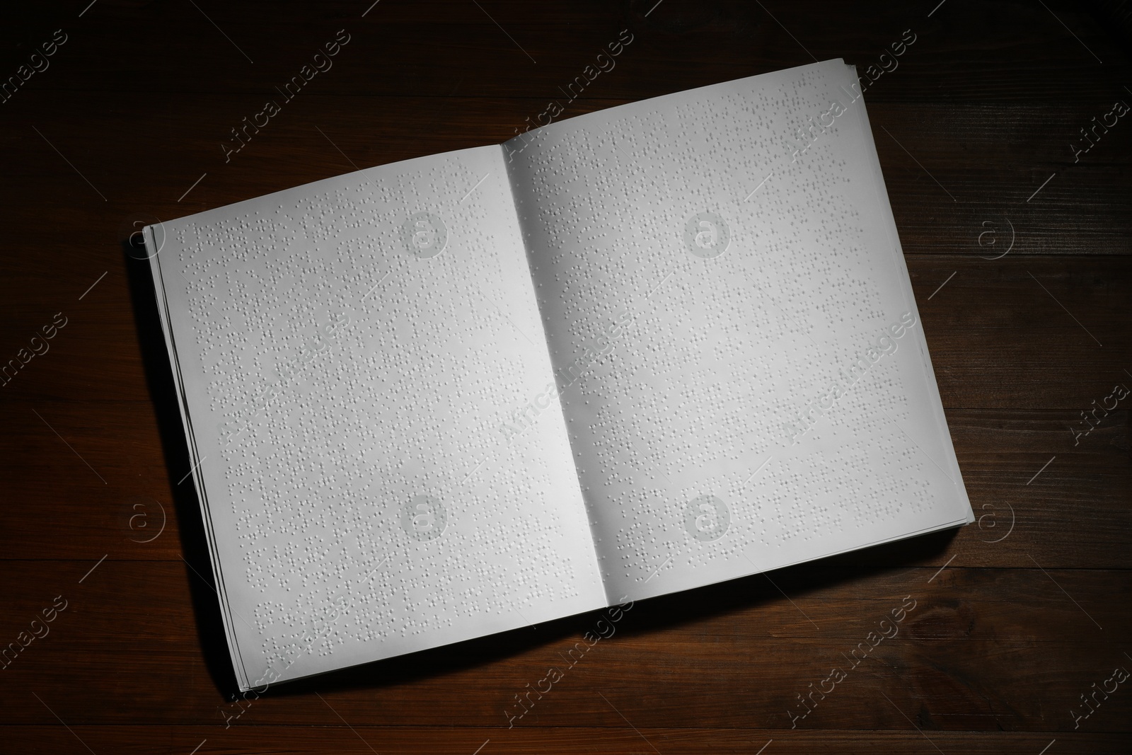 Photo of Book with Braille text on wooden table, top view. Education and leisure for blind people