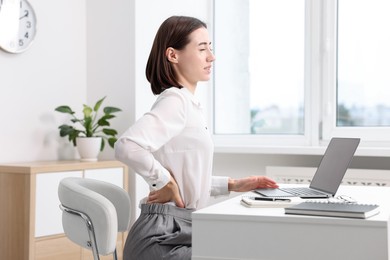 Photo of Woman suffering from back pain in office. Symptom of poor posture