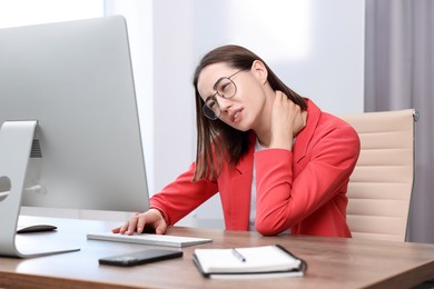 Photo of Woman suffering from neck pain in office. Symptom of poor posture
